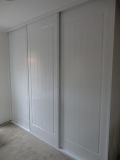 an empty room with white closet doors and carpet