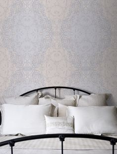 a bed with white pillows on top of it next to a wallpapered wall