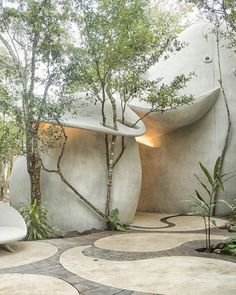 an outdoor area with concrete walls and trees in the background, including two white chairs