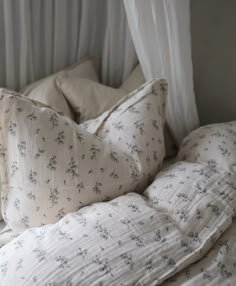 a bed with white linens and pillows on top of it next to a window