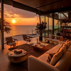 a living room filled with furniture next to the ocean at sunset or sunrise hours end