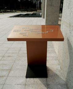 a table sitting on the side of a building next to a tall pillar with writing on it