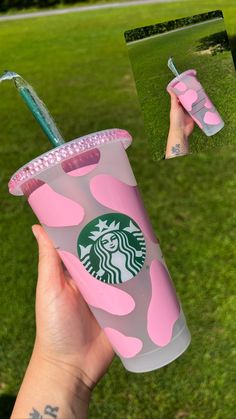 the starbucks cup has pink camo on it and is being held up by someone's hand