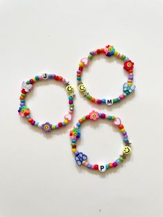 three bracelets with letters and smiley faces on them, all made out of beads