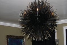 a black chandelier hanging from the ceiling in a room with two pictures on the wall