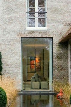 the reflection of a living room and sitting area in a house's water feature