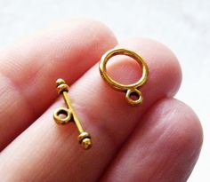 a small gold colored ring with a key on it's side in someones hand