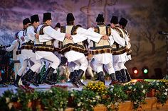 a group of men in white and black outfits on stage with one man holding his arms around the other