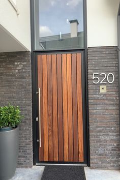 a large wooden door sitting in front of a brick building next to a potted plant