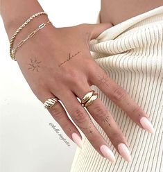 a woman's hand with two rings on it and a star tattoo on the middle finger