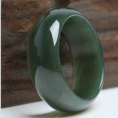 a green ceramic ring sitting on top of a wooden table next to a piece of wood