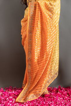 Yellow and orange saree with an ombre woven stripe base highlighted by zardozi embroidery. Comes with matching embroidered blouse.
Components: 2
Pattern: Embroidered
Type Of Work: Zardozi, Gotapatti
Neckline: Round
Sleeve Type: Half
Fabric: Tissue
Color: Orange,Yellow
Other Details: 
Woven zari stripes
Placed embroidery
Occasion: Mehendi and Haldi,Sangeet - Aza Fashions Ombre Saree, Zardozi Embroidery, Orange Saree, Blouse For Women, Fashion App, Saree With Blouse, Blouse Online, Embroidered Blouse, Aza Fashion