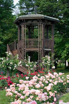 a wooden gazebo surrounded by flowers and trees