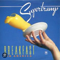 a hand holding a yellow and white object with the words breakfast in america on it