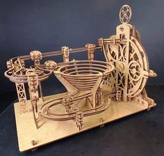 a wooden model of a machine with gears on it's sides and wheels in the center