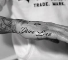 a person with a tattoo on their hand that says, divine love written in cursive writing