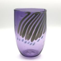 a purple glass vase sitting on top of a white table