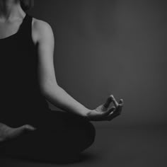 a woman is sitting in the middle of a yoga pose with her hands crossed out