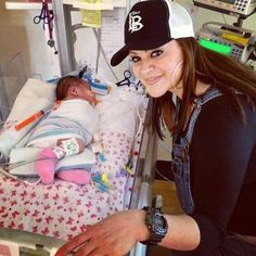 a woman holding a baby in a hospital bed with an oxygen tube attached to it