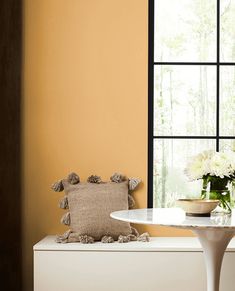 a white table and chair in front of a window with flowers on the windowsill