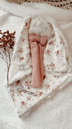 a baby's pink bow tie laying on top of a blanket next to a plant