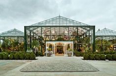 a large glass building with lots of plants in it's front entrance and walkway