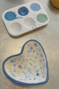 a heart shaped dish with paint in it on a table next to an empty tray