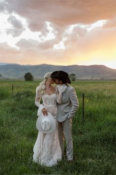 a bride and groom kissing in a field