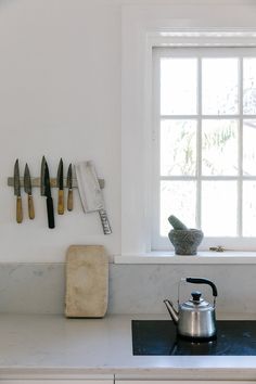 a tea kettle sitting on top of a stove next to a pot and knifes