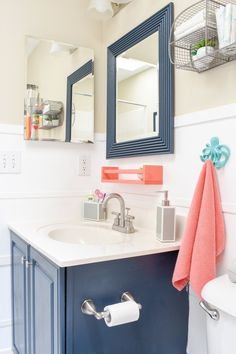 a bathroom with blue cabinets and a white toilet next to a mirror on the wall