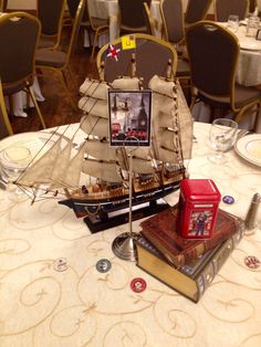 a table topped with books and a model ship on top of it's head