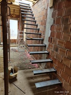 a set of stairs leading up to a brick wall in an unfinished room with scaffolding