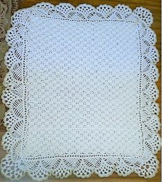 a white crocheted doily on top of a wooden table next to a rug