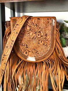 9" H x 10" W x 5" D Western style bag with cowhide and leather adorned with leather fringe Flap snaps closed and has zipper closure at top zipper and open pocket inside tooled leather strap - 48” crossbody (removable Select cowhide pattern option from drop down menu. Cowhide and leather colors vary. Select exact item from drop down. Not customizable - handmade by American Darling Products Western Style Purse, Cowhide Pattern, Nashville Outfit, Fringe Handbags, Leather Colors, Tan Handbags, Nashville Outfits, Fringe Purse, Leather Saddle Bags