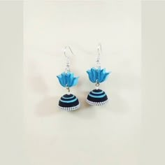 a pair of blue and black earrings with flowers hanging from it's ear wires