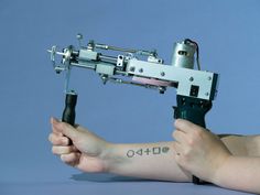 a person holding an arm with a tattoo machine on it's arm and the arm is being held up