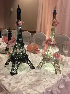 the table is decorated with pink flowers and lit up eiffel tower