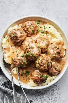 a bowl filled with meatballs and gravy on top of mashed potatoes