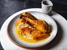 two pieces of chicken sitting on top of a plate next to a cup and sauce