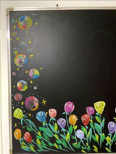 a chalkboard with flowers and planets painted on it in front of a black background