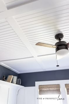 a ceiling fan is mounted to the ceiling in a room with blue walls and white shutters