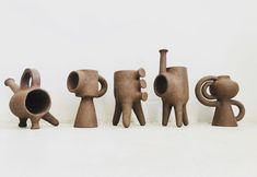 five clay figurines are lined up in the same row, each with different shapes and sizes