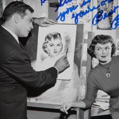 an old photo of a man and woman in front of a drawing on a easel