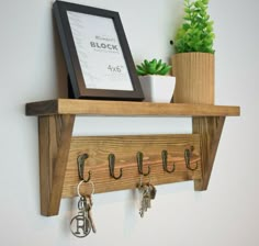 a wooden shelf with key hooks and keys hanging on it's sides next to a potted plant