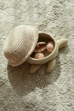 a hat and some rocks in a small bowl on the ground with sand around it