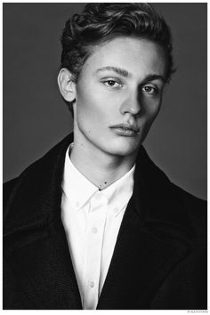 a black and white photo of a young man in a blazer looking at the camera