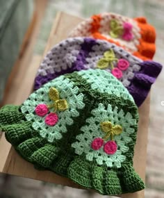 three crocheted hats sitting on top of a wooden table