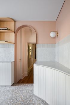 a hallway with pink walls and marble counter tops, along with an arched doorway leading to another room