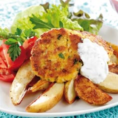 a white plate topped with potato cakes next to a pile of fries and salad on a blue table cloth