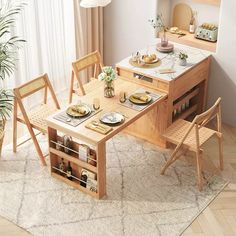 a kitchen table with chairs and plates on it in front of a potted plant